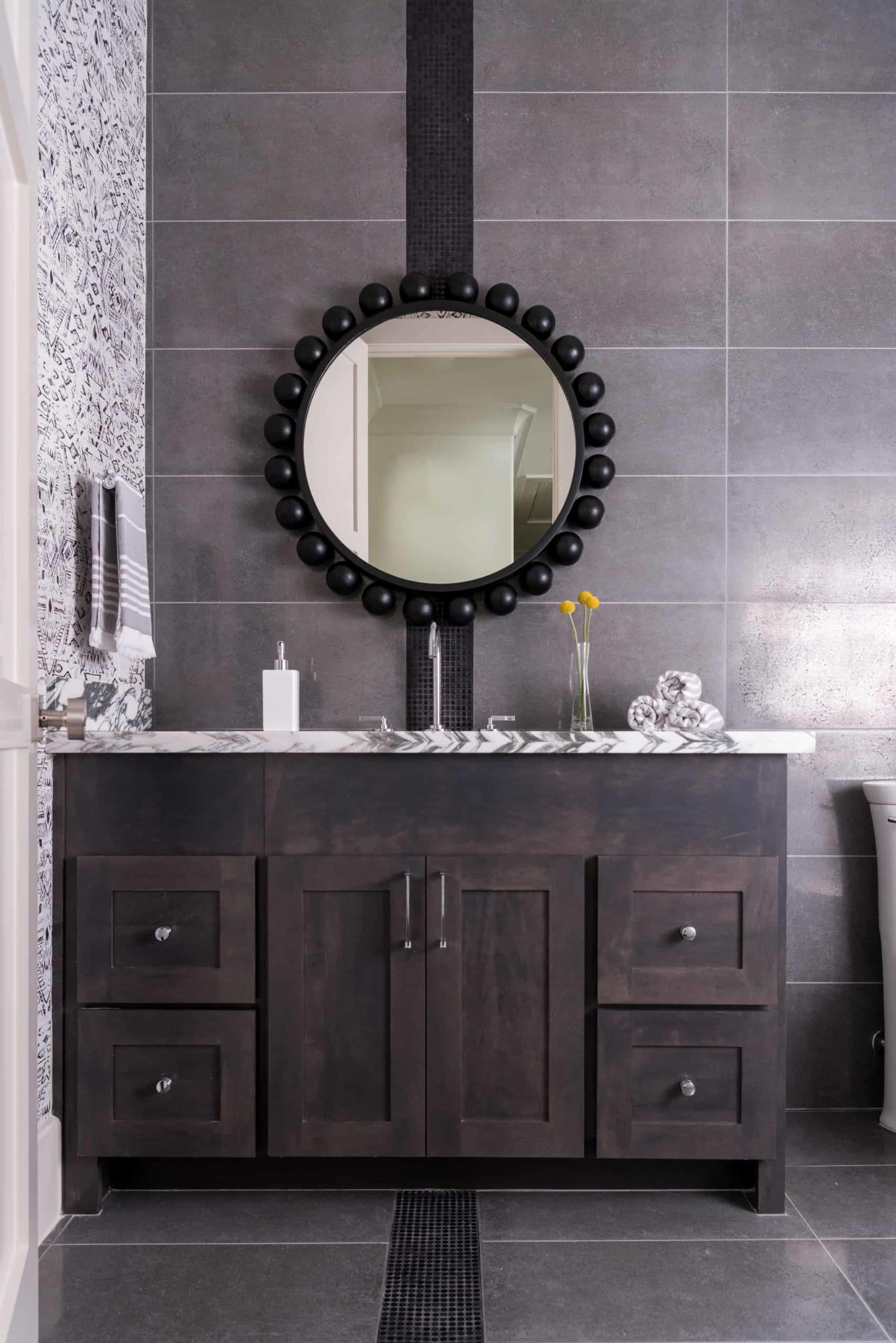 A circular mirror in a moody, handsome bathroom