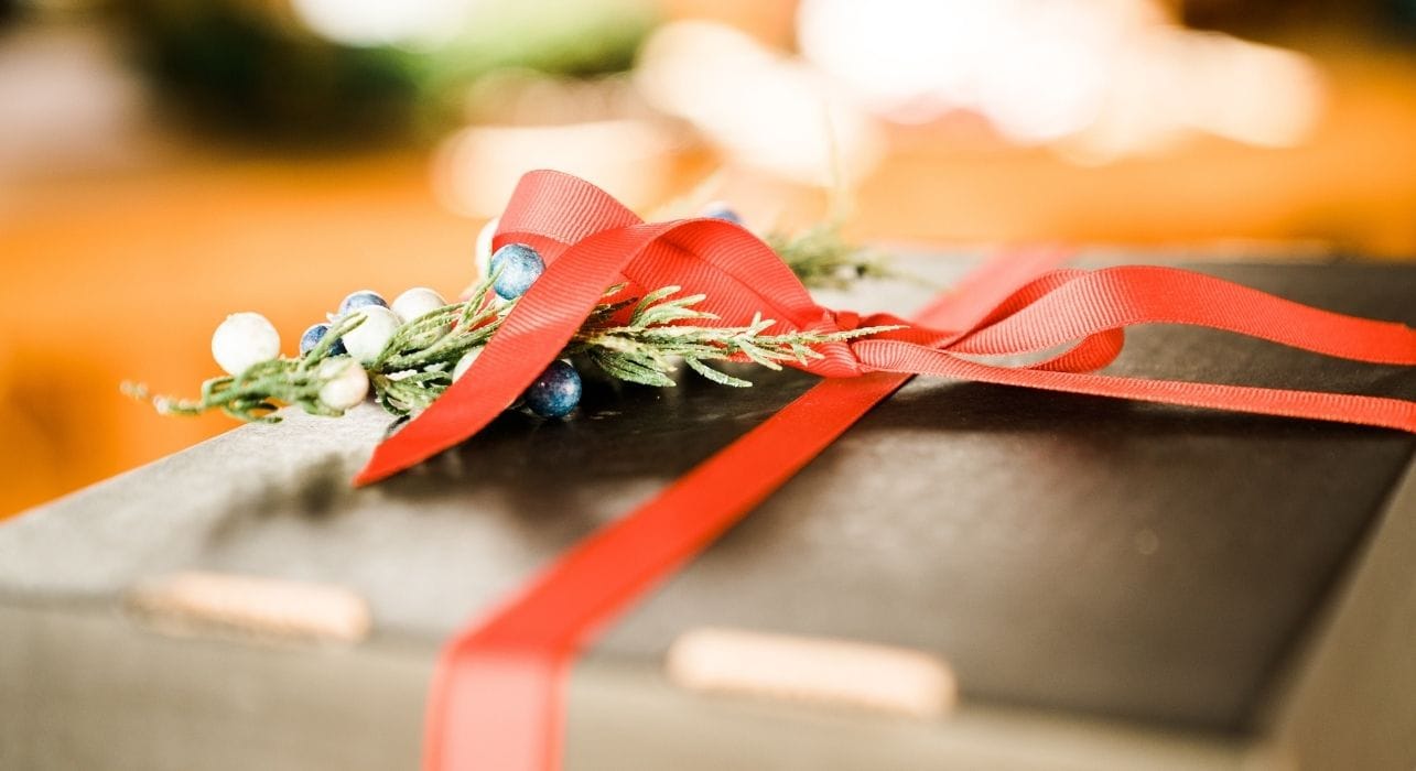 Beautifully wrapped present with red ribbon and greenery
