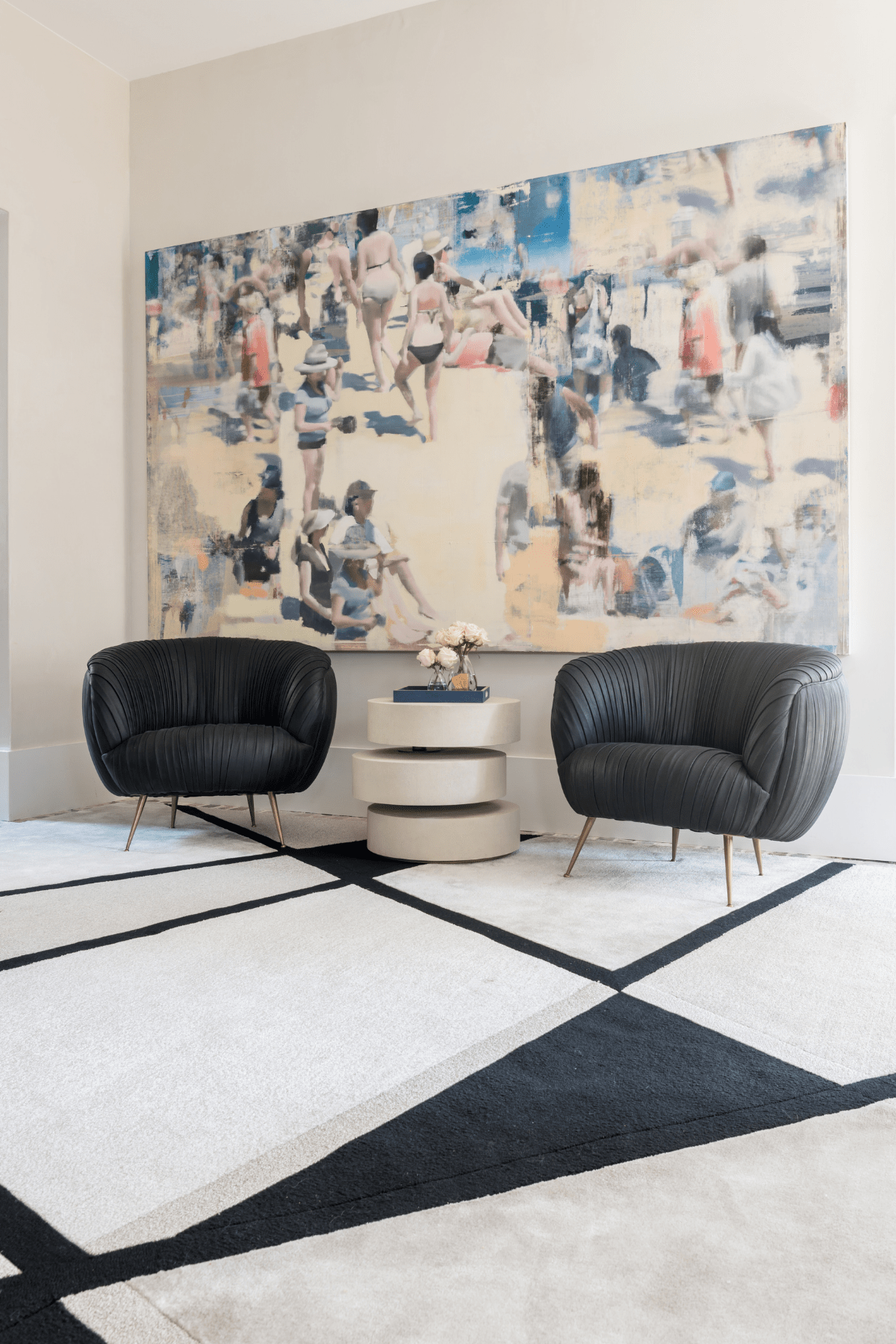 Two black Kelly Wearstler chairs on geometric carpeting in front of a beach art piece.