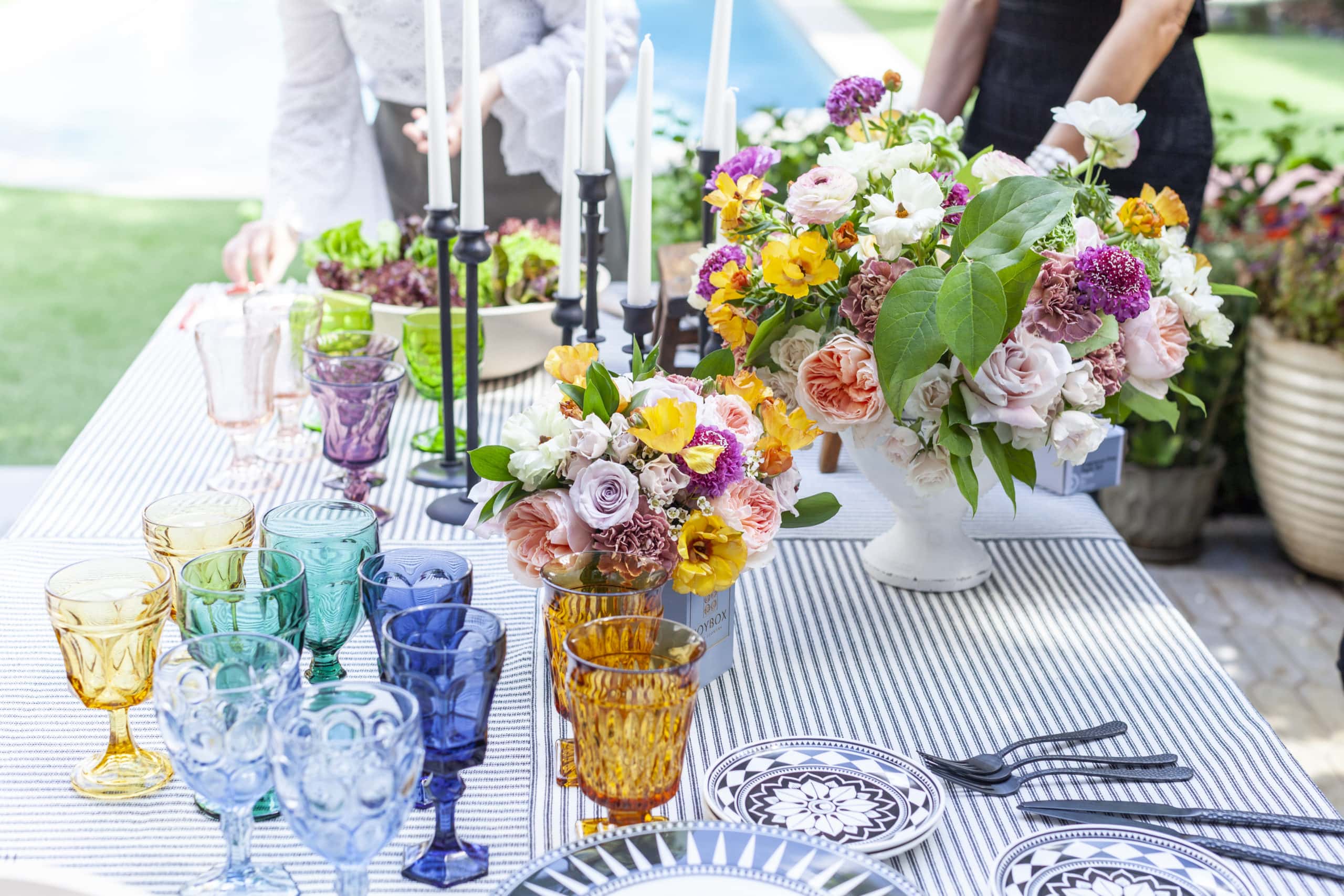 A colorful tablescape for dining al fresco with flowers and vintage glassware