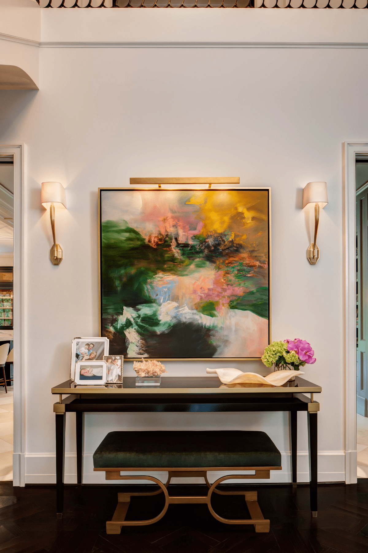 An desk area featuring a vibrant piece of artwork above a desk and bench.