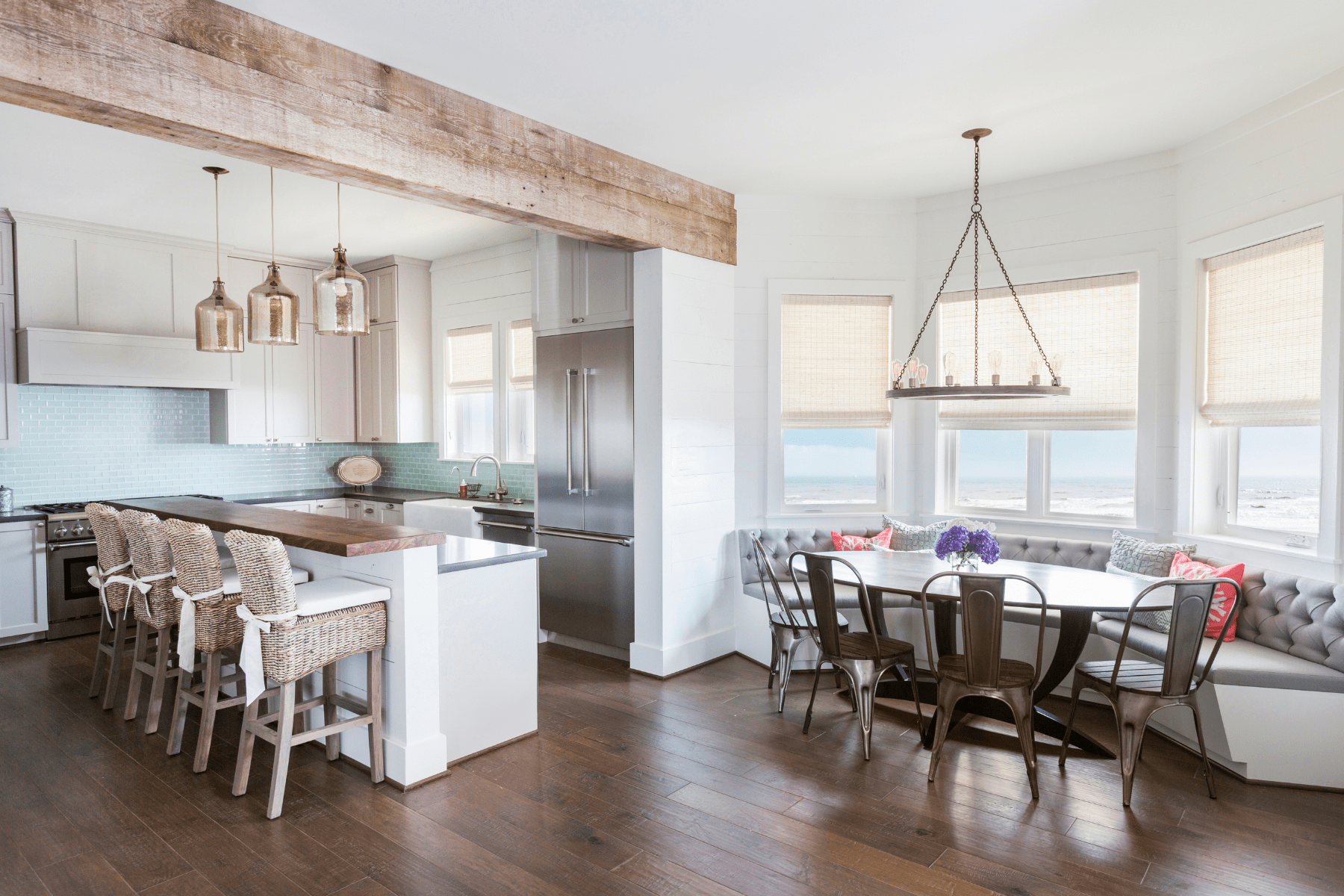 An eat-in kitchen at the Sandhill Shores home featuring a light palette illuminated by sunlight and custom furnishings that bring a cozy feel to the space.