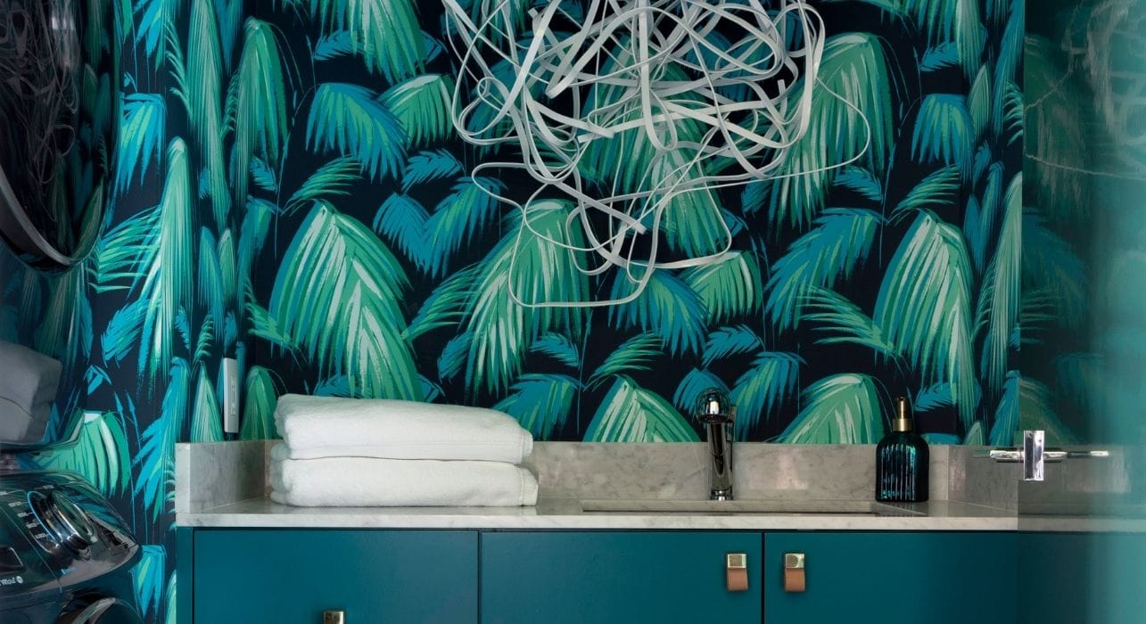 Dark and moody laundry room in River Oaks with tropical wallpaper
