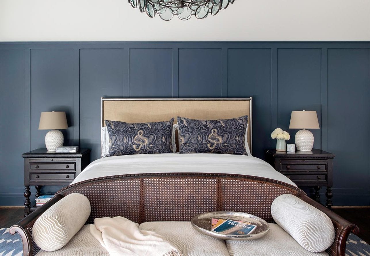 Blue paneling lines the back wall of this master suite and contrasts against the white bedding and ceiling