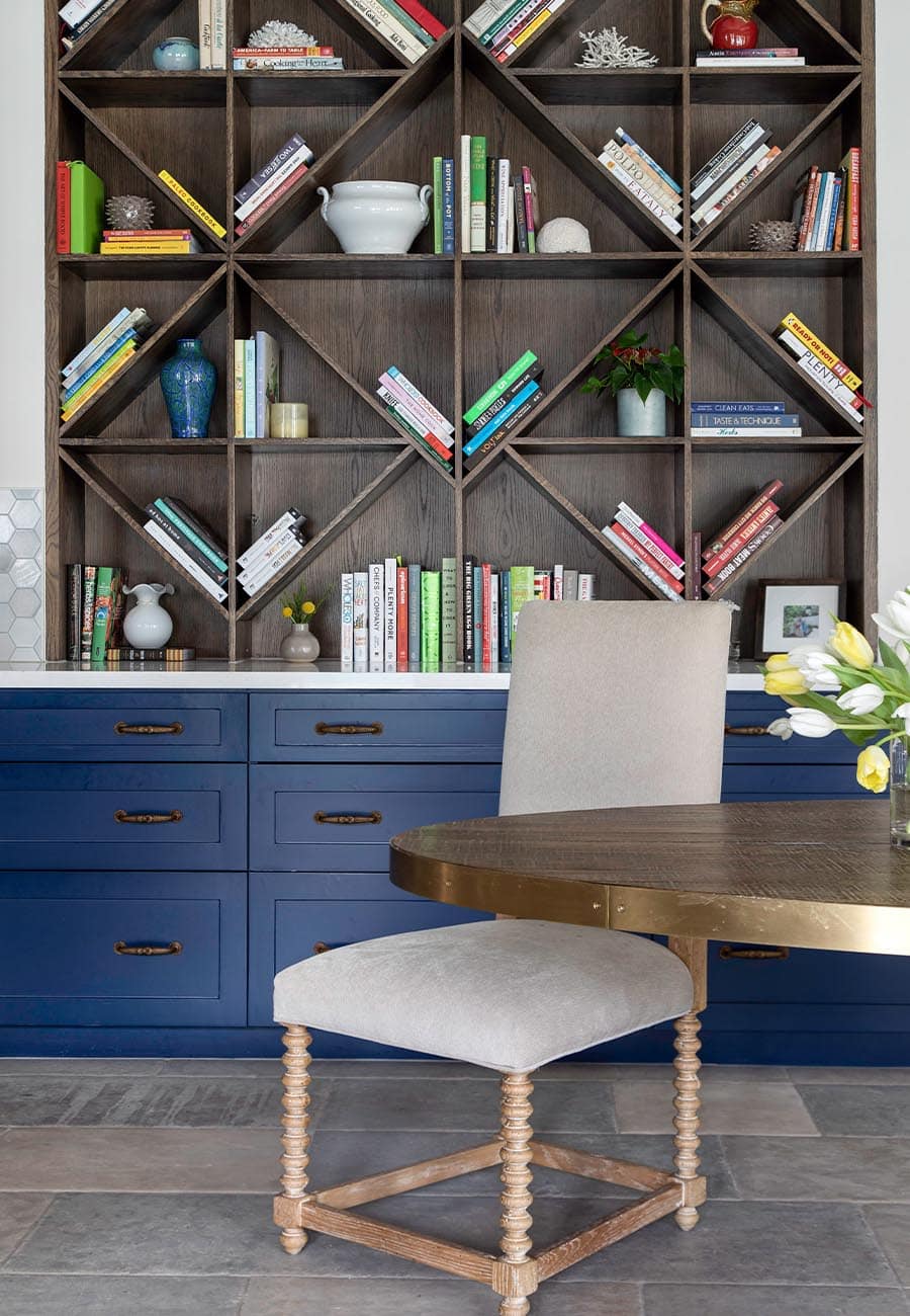 A desk chair positioned against blue cabinets and a wooden bookshelf