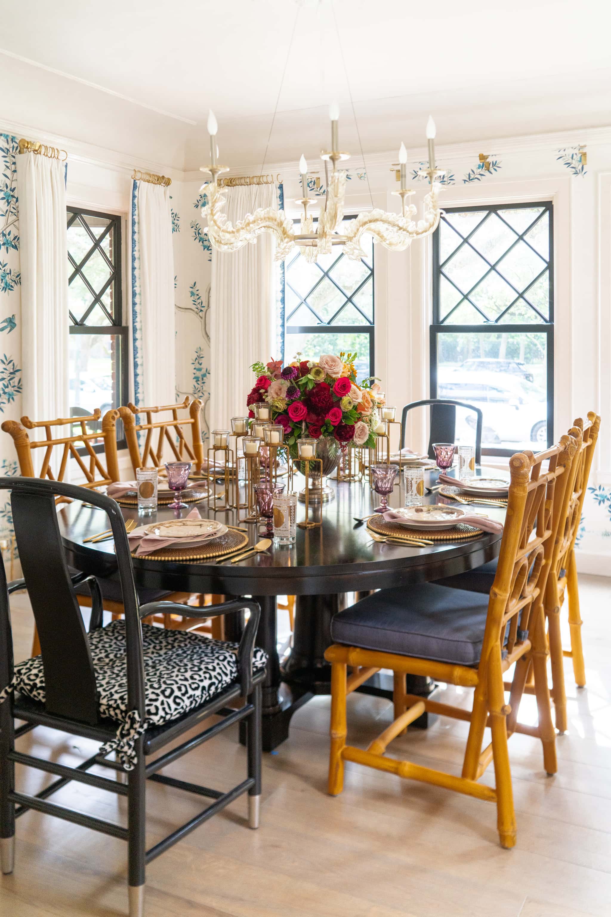 A view of a dining room with Gracie wallpaper and black table with bamboo dining chairs, in the home of Laura Umansky