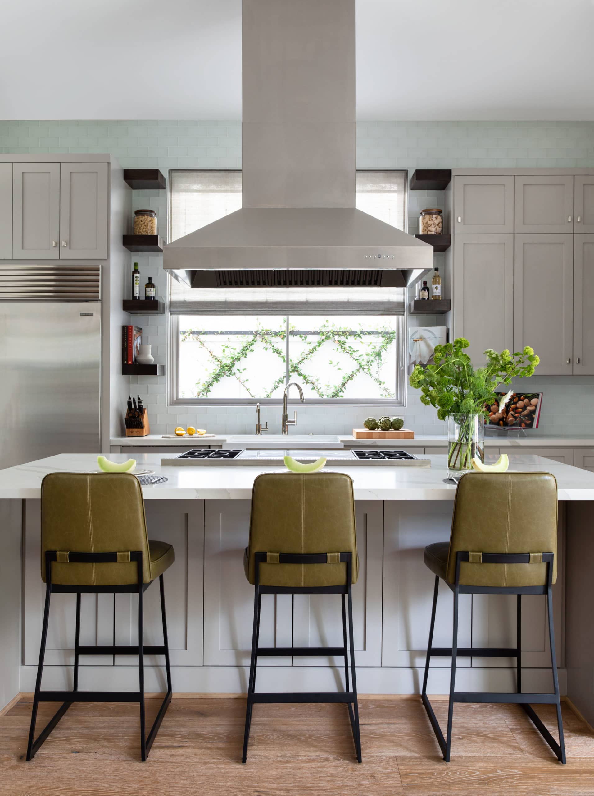 The kitchen at Dunstan with wall tile, barstools, and a large vent hood