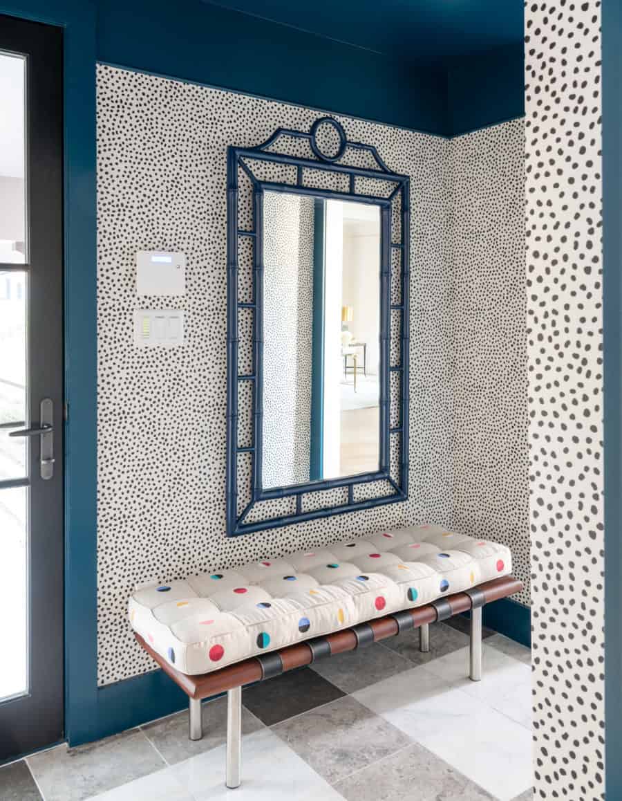 A mudroom with fun polka dotted walls and bench with vintage mirror