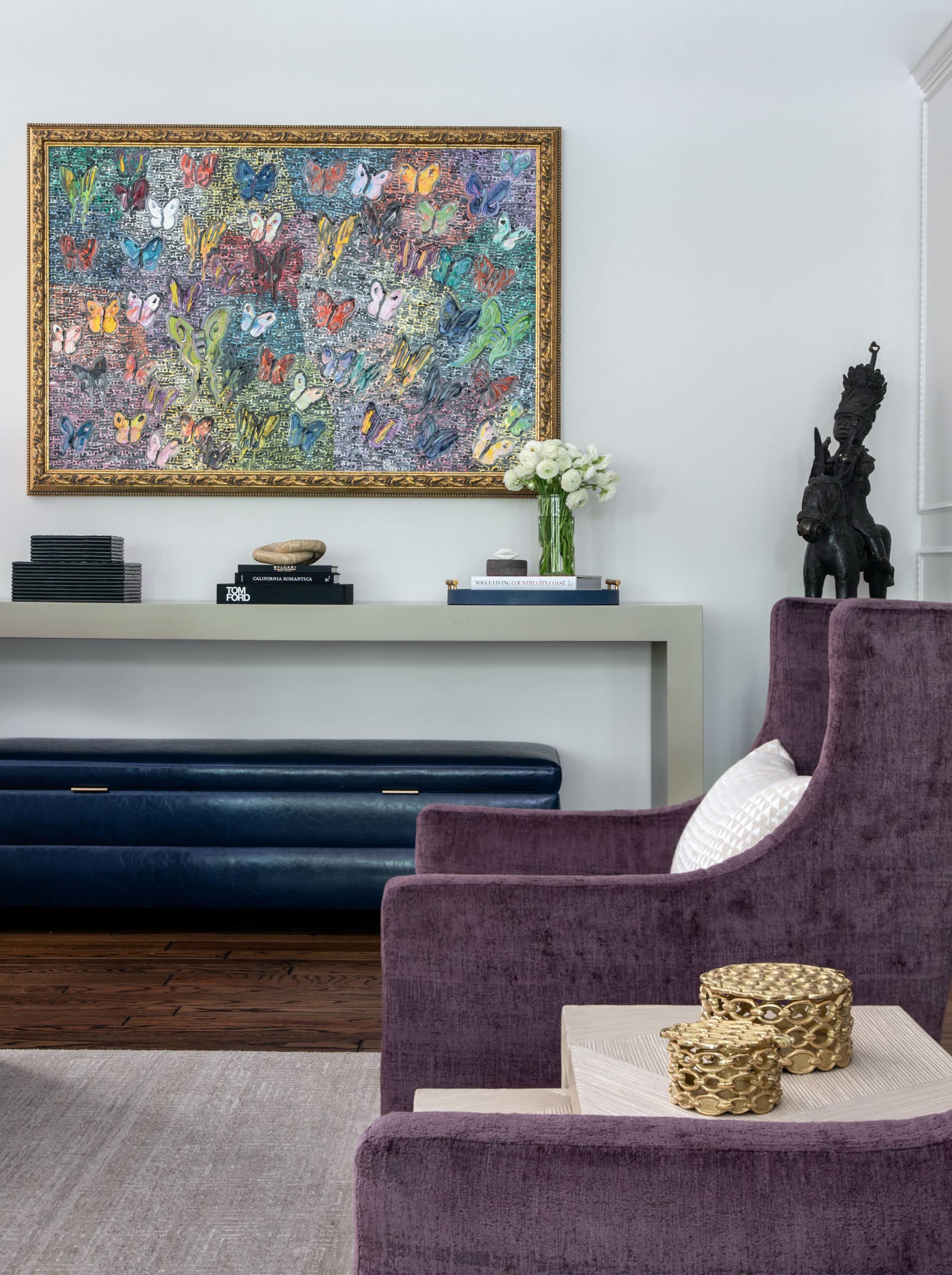 Colorful Hunt Slonem piece hanging in a living room with purple accent chair