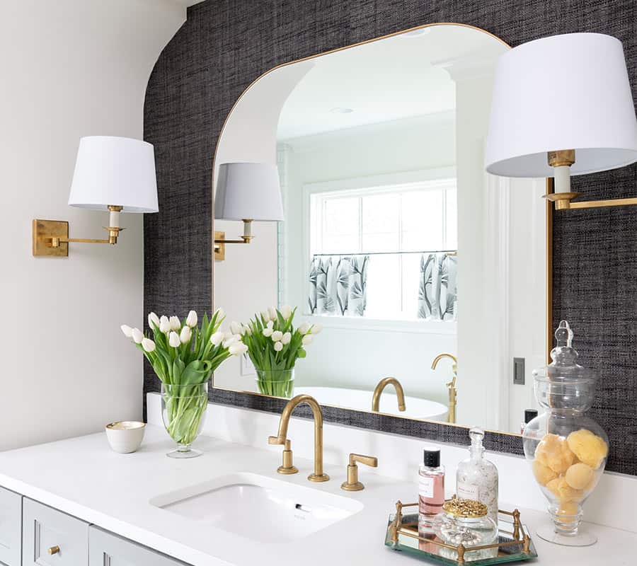 A custom-designed vanity with pendant lights and navy grasscloth