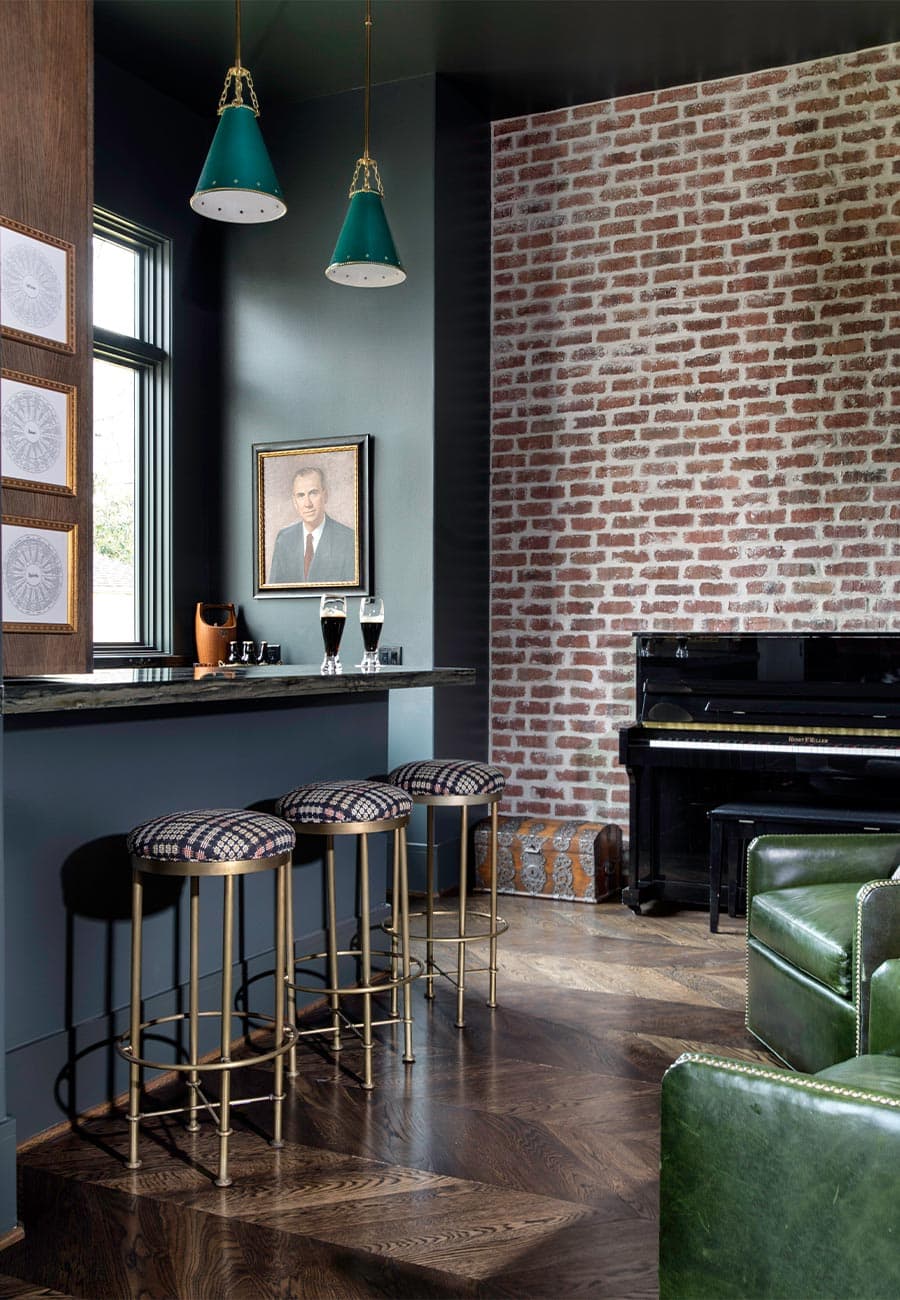 A home pub with exposed brick walls and upholstered, plaid bar stools