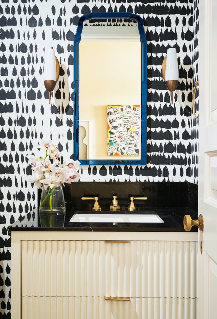 The power room flaunts bold pattern wallcoverings and a beautiful royal blue boarder mirror.